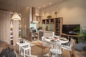 A modern kitchen with a dining area, built-in shelves, and a flat-screen TV. - Ninemia Shore Retreat | Beachfront Escape with Hot Tub (Stalida)