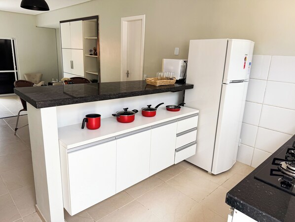 Eine moderne Küche mit schwarzer Arbeitsplatte, weißen Schränken, einem Kühlschrank und einem Gasherd.