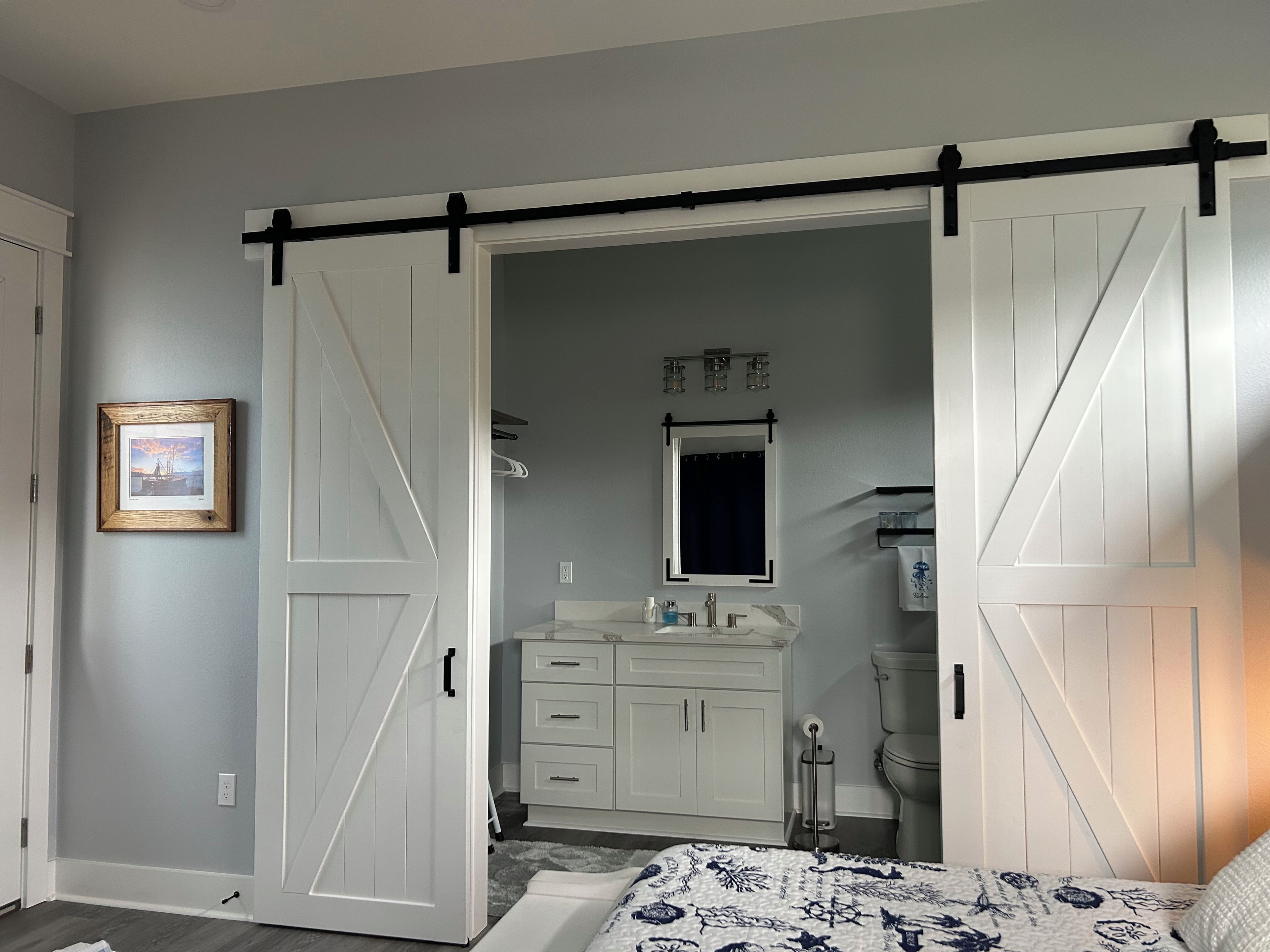 Une chambre à coucher comprenant un lit, une commode, une coiffeuse et un placard avec une porte coulissante de style grange.