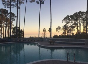 Une piscine avec des chaises longues et une vue sur le coucher de soleil.