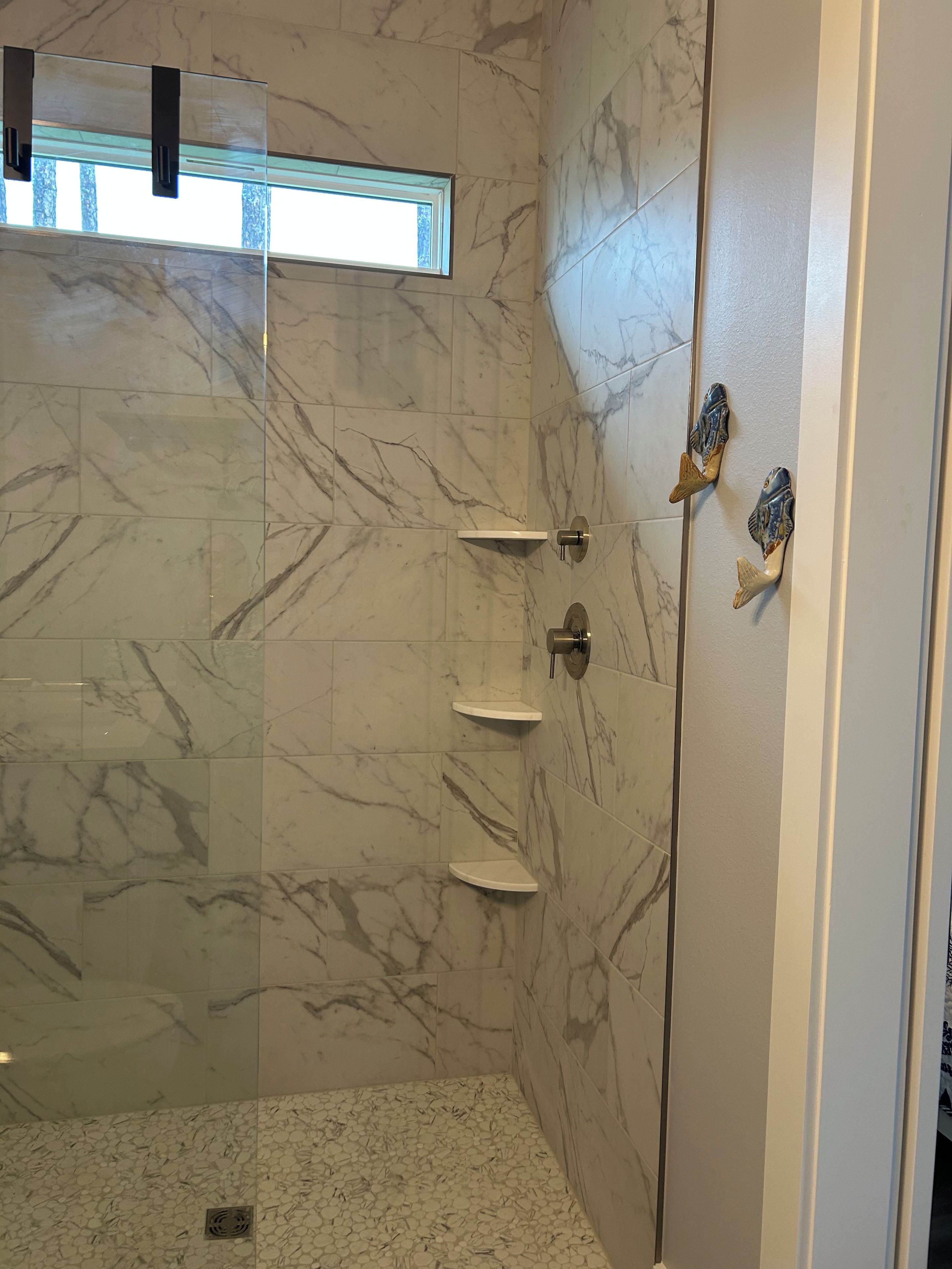 Ein Badezimmer mit Marmorwänden, einer Duschkabine aus Glas und einem kleinen Fenster.
