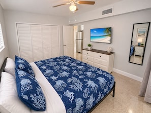 A bedroom with a bed, a dresser, a ceiling fan, a painting, and a mirror. - 1BR Beachfront Cottage, Dogs Welcome, Steps to the Sand (Redington Shores)