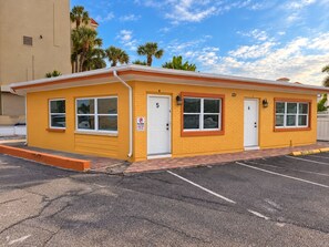 A yellow building with two doors, numbered 5 and 6, and a parking lot in front. - 1BR Beachfront Cottage, Dogs Welcome, Steps to the Sand (Redington Shores)
