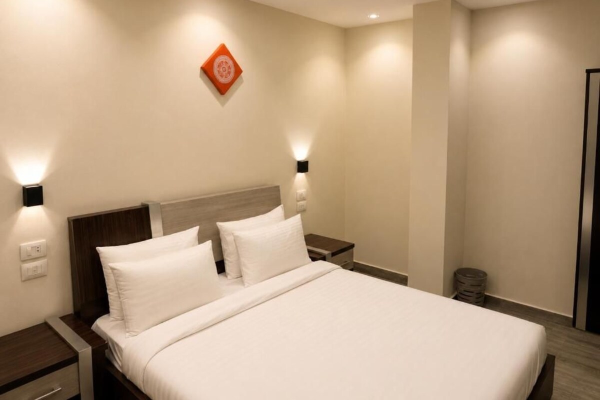Una habitación de hotel con cama, mesitas de noche e iluminación en la pared.