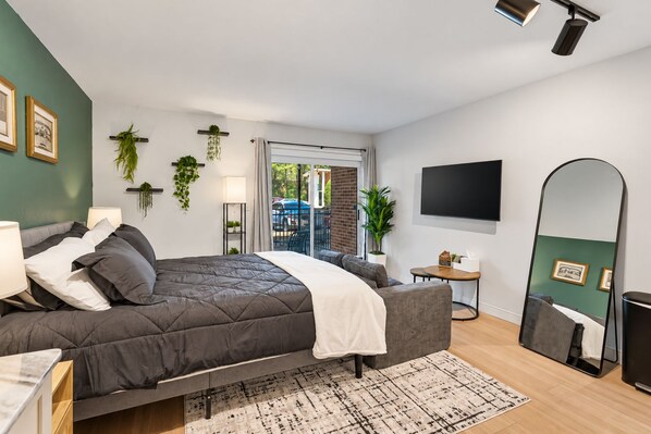 Ein modernes Schlafzimmer mit einem Bett, Nachttischen, einem Fernseher und einem großen Spiegel.