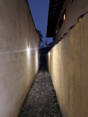 Une ruelle étroite aux murs en béton et au sol accidenté.