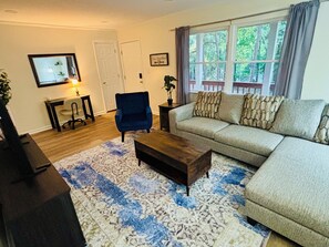 Een woonkamer met een bank, fauteuil, salontafel en vloerkleed.