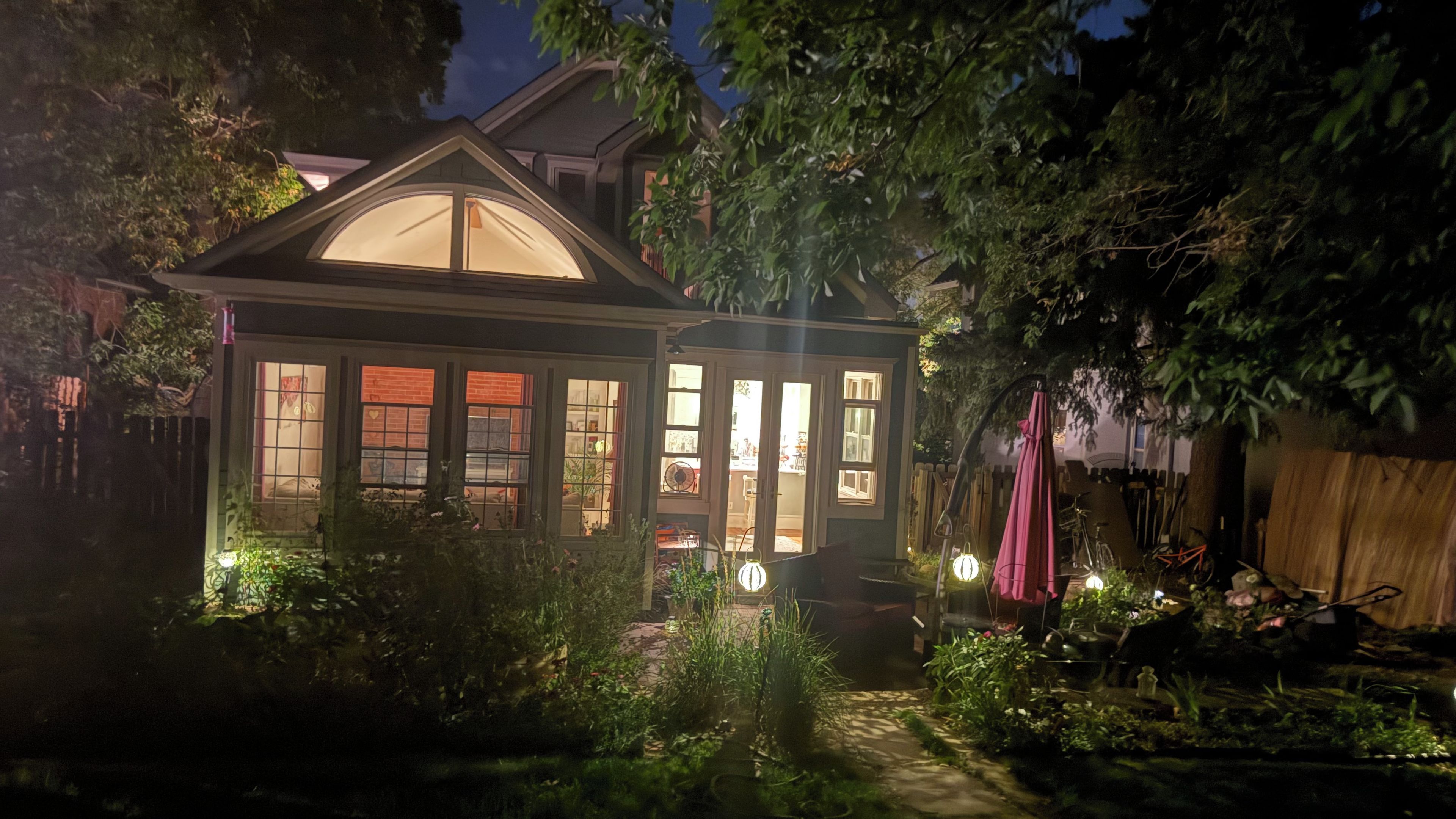 A house with a large bay window, a covered porch, and a garden area with plants and a pathway.