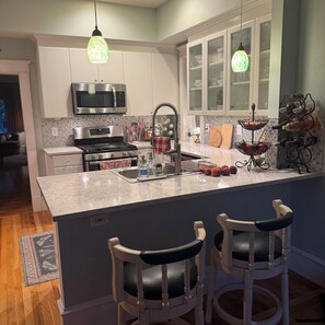 A kitchen with a central island, bar stools, a microwave, a stove, and a wine rack. - Stunning Victorian home with easy access to the best of Boulder - and Sundance! (Boulder)