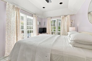 A bedroom with a large bed, a television, and a window with blinds. - Cozy 2-Bedroom Island Retreat for 4 in Old Town Key West by the Tropical Pool (Key West)