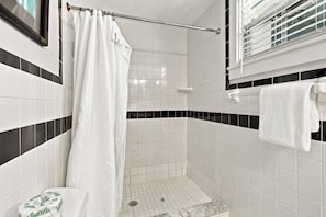 A bathroom with white tiles, a shower curtain, a towel rack, and a toilet. - Cozy 2-Bedroom Island Retreat for 4 in Old Town Key West by the Tropical Pool (Key West)