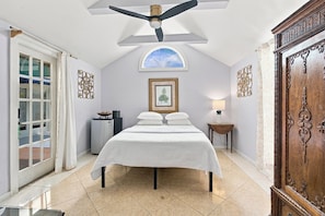 Une chambre à coucher avec un lit, un ventilateur de plafond, une fenêtre et une porte.