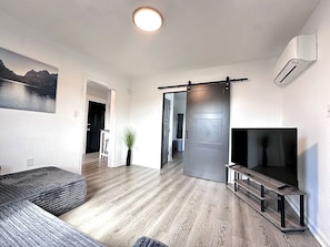 Un salon moderne avec un canapé, un téléviseur et une porte coulissante.