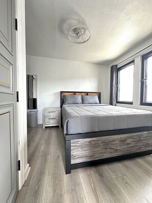 Ein Schlafzimmer mit einem Bett, Nachttischen, einem Deckenventilator und einem Fenster.