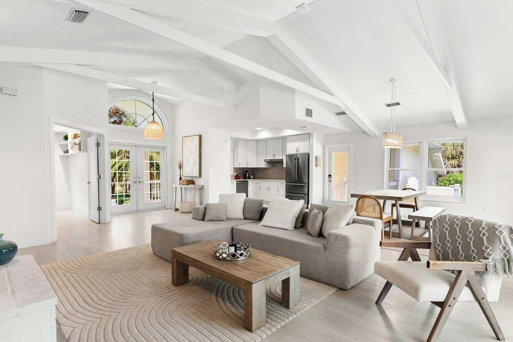 A modern living room with a sectional sofa, a coffee table, and a dining area with a table and chairs.