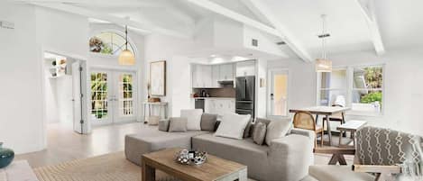 A modern living room with a sectional sofa, a coffee table, and a dining area with a table and chairs.