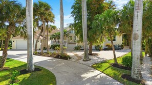 A residential area with palm trees, a driveway, and a house with a garage. - Coastal Retreat - Sanibel Island Home, Pool and Beach Access! (Sanibel)