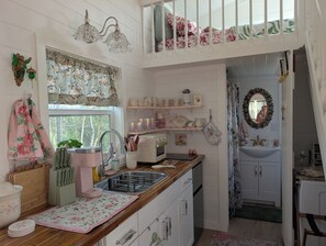 A kitchen with a wooden countertop, a sink, and a window with floral curtains.