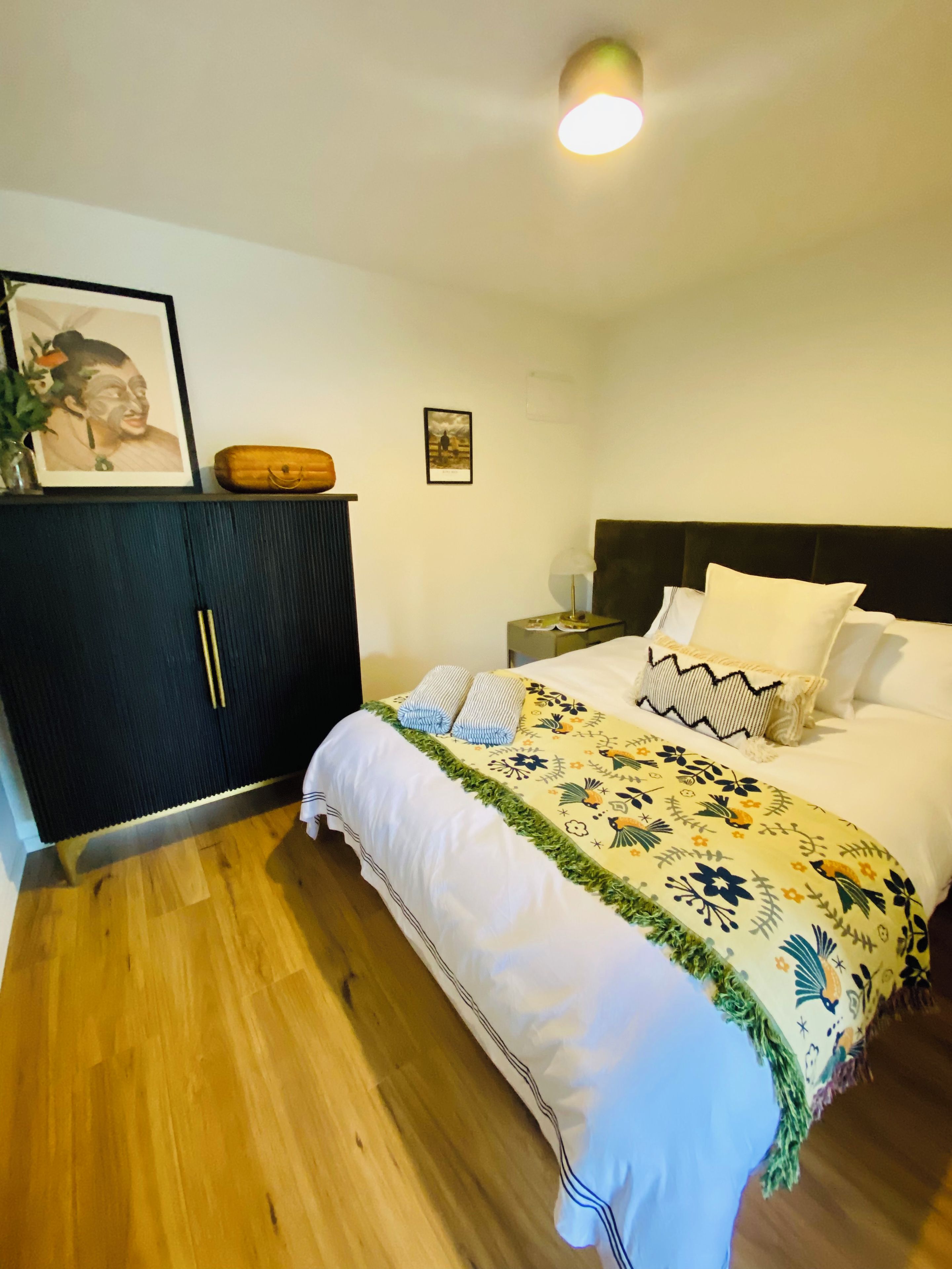 A bedroom with a bed, a nightstand, a dresser, and a framed picture on the wall.