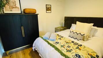 A bedroom with a bed, a nightstand, a dresser, and a framed picture on the wall.