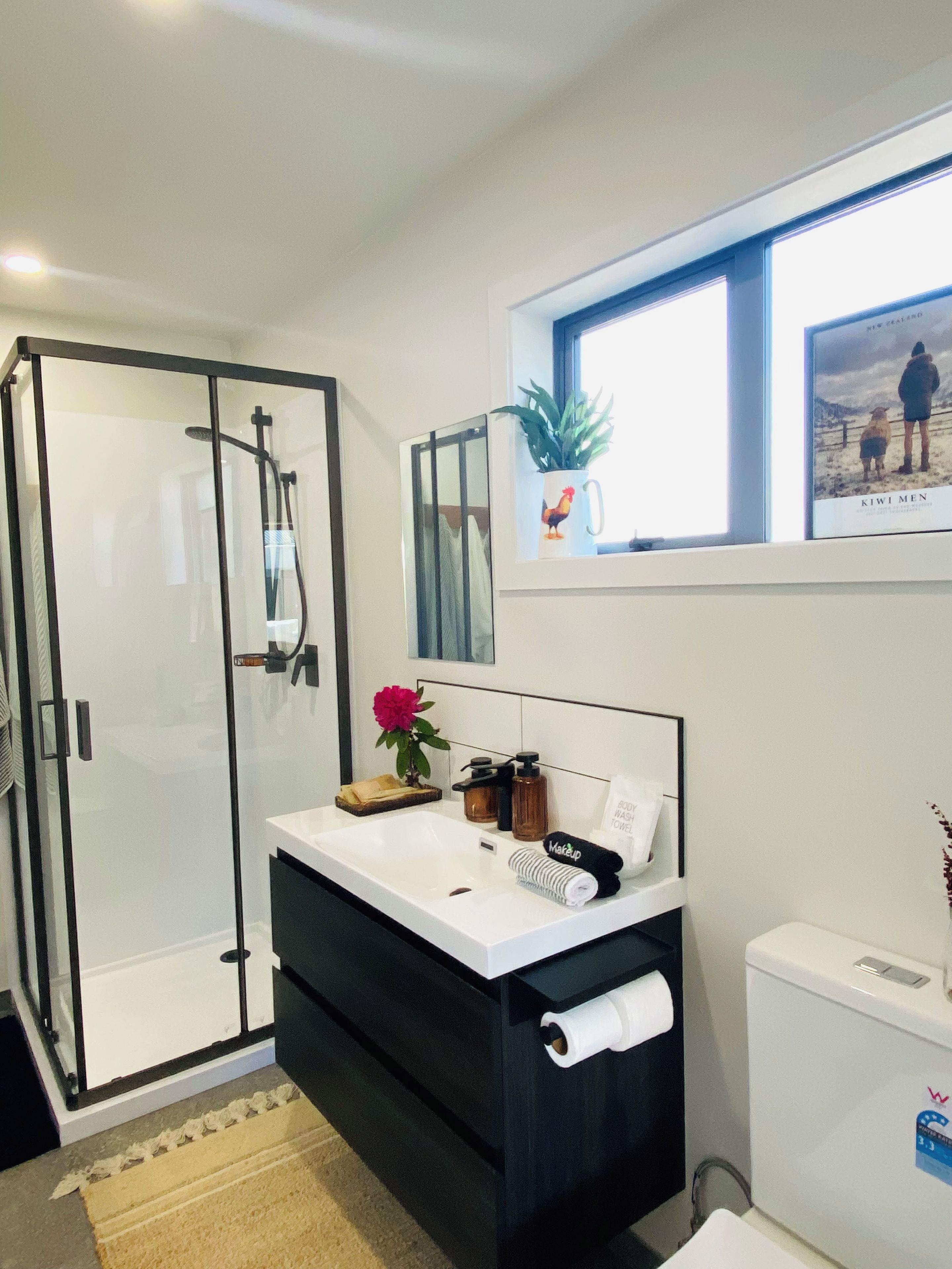 A modern bathroom with a glass shower enclosure, a vanity with a mirror, and a toilet.