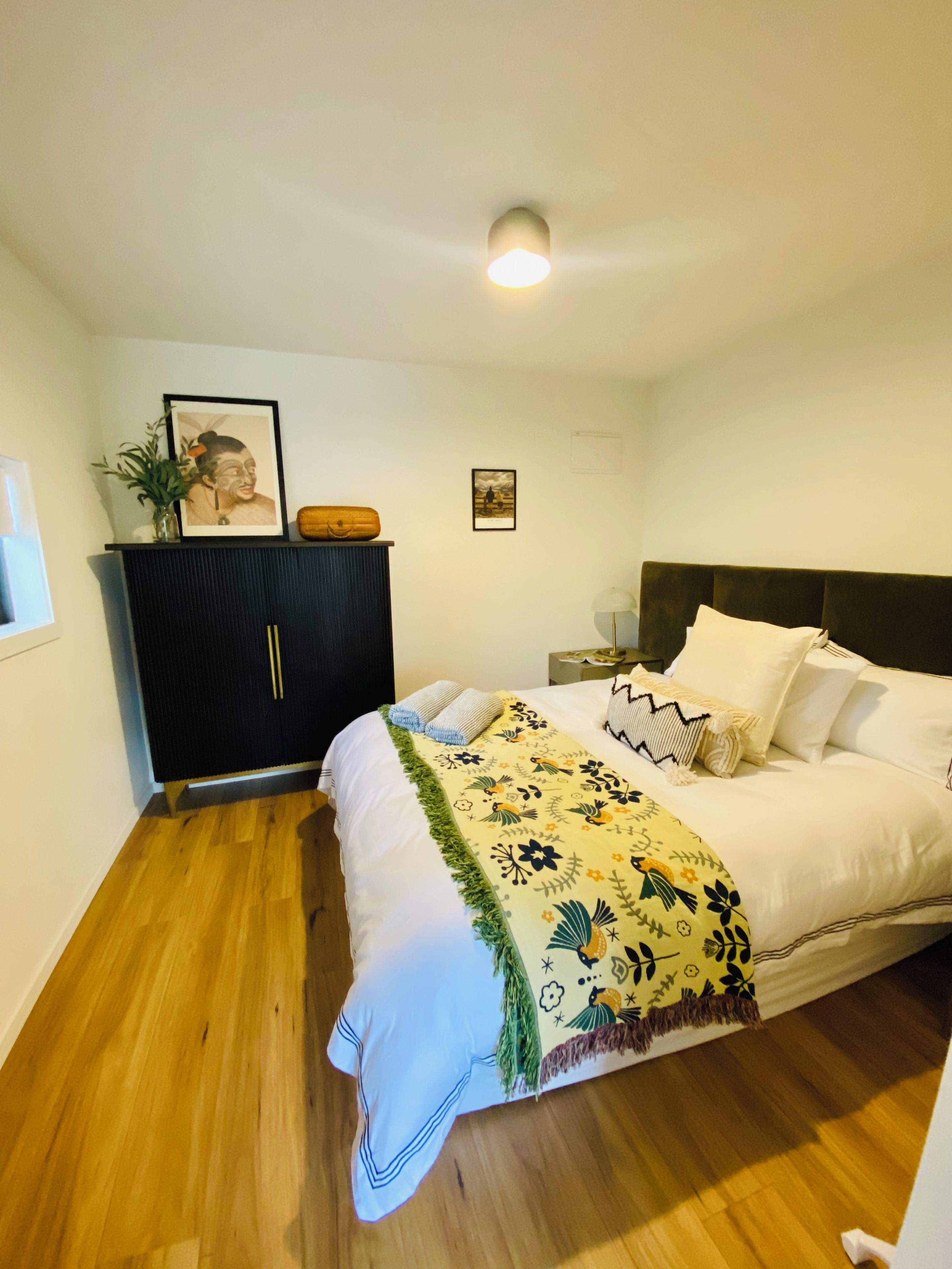 Un dormitorio con cama, mesita de noche, cómoda y luz de techo.