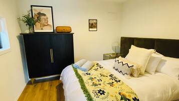 Un dormitorio con cama, mesita de noche, cómoda y luz de techo.