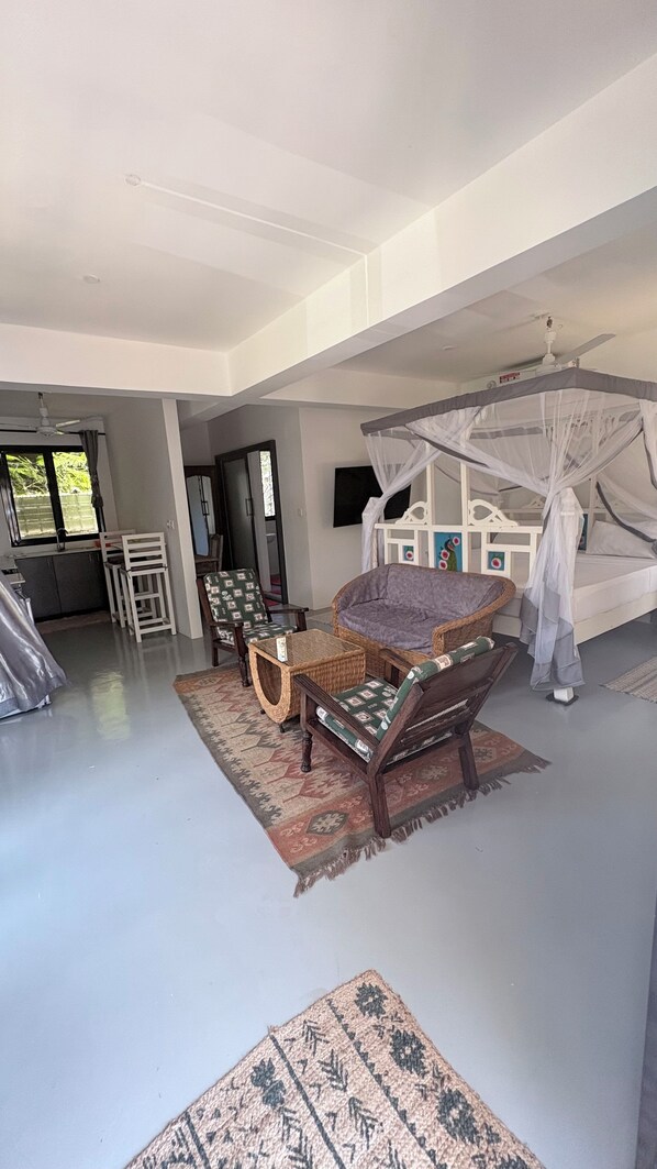 Ein geräumiges Wohnzimmer mit einer Couch, Sesseln, einem Couchtisch und einem Deckenventilator.
