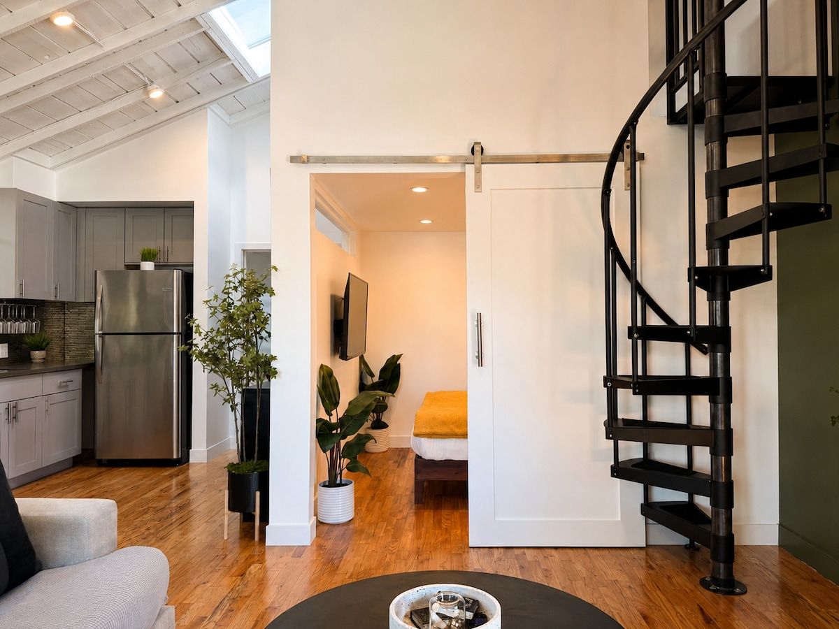 A modern interior with a kitchen, a dining area, and a bedroom.