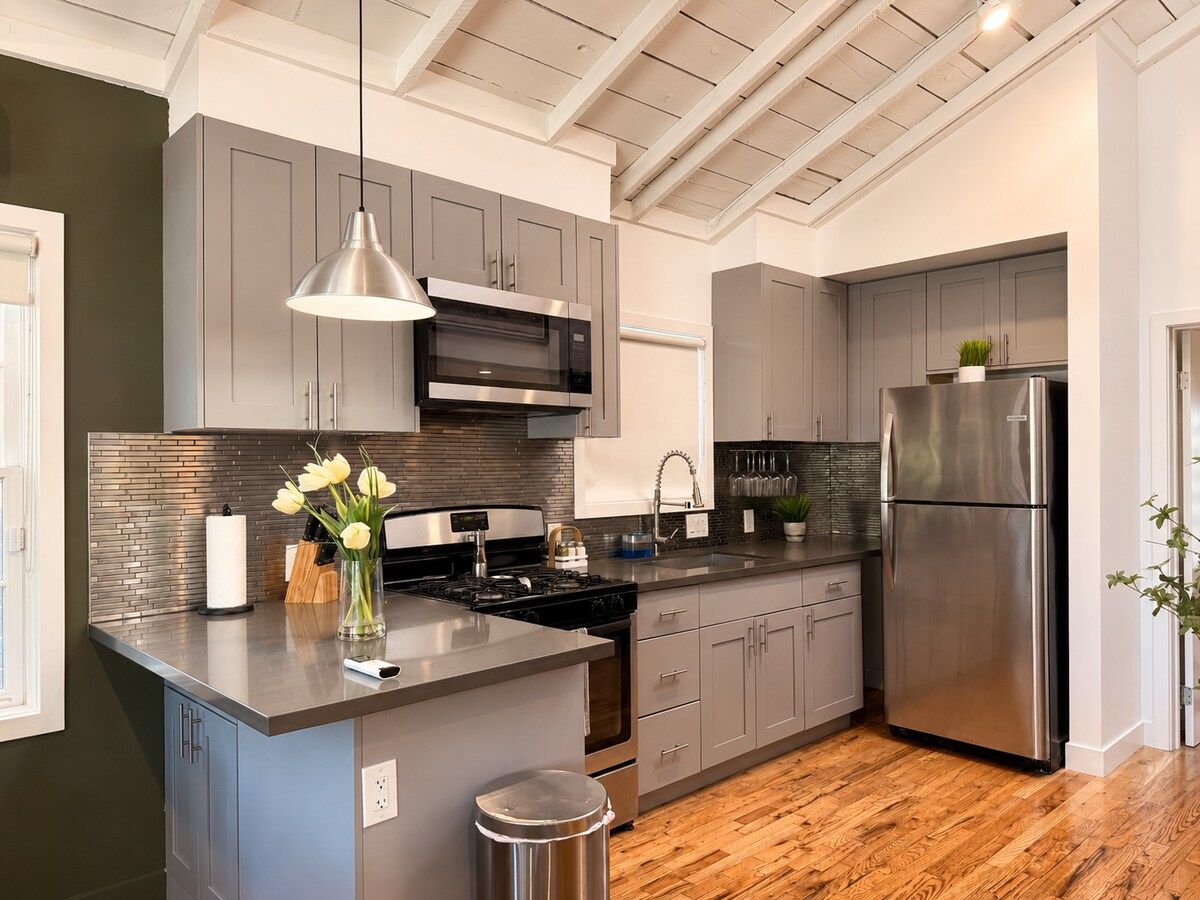 A modern kitchen with stainless steel appliances, a central island, and a pendant light.
