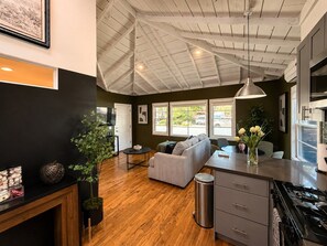 Een moderne keuken met een eethoek, houten vloeren en een hoog plafond met zichtbare balken.