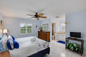 Ein Schlafzimmer mit Bett, Kommode, Fernseher und Deckenventilator.