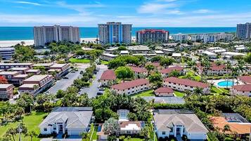 A coastal residential area with multiple-story buildings, a beach, and a clear sky.