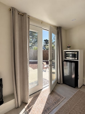 A room with a sliding glass door leading to an outdoor patio, a refrigerator, and a microwave. - Serene studio apartment in beautiful Daly City perfect for relaxing (Daly City)