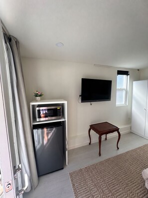 Een knus woongedeelte met een kitchenette, een wandtelevisie, een klein houten tafeltje en een raam met uitzicht.
