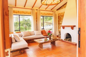 Ein Wohnzimmer mit einer Couch, einem Couchtisch, einem Kamin und großen Fenstern.