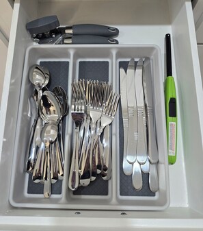 Un cassetto suddiviso in scomparti con vari utensili, tra cui forchette, coltelli e cucchiai.