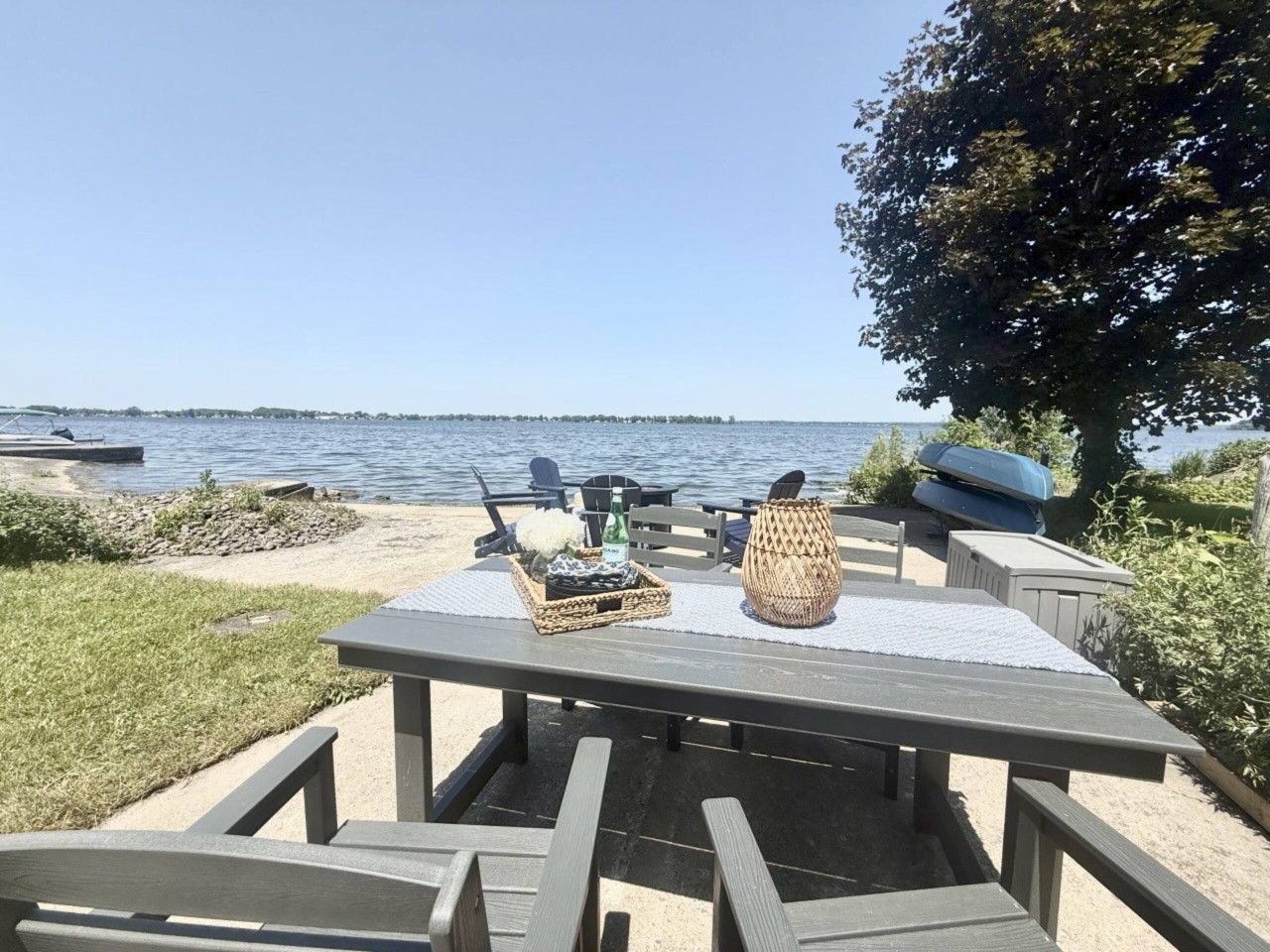 Een eethoek buiten met een tafel gedekt voor twee personen, een rieten mand en een decoratieve vaas.