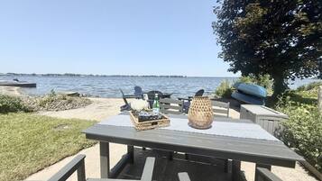 Een eethoek buiten met een tafel gedekt voor twee personen, een rieten mand en een decoratieve vaas.