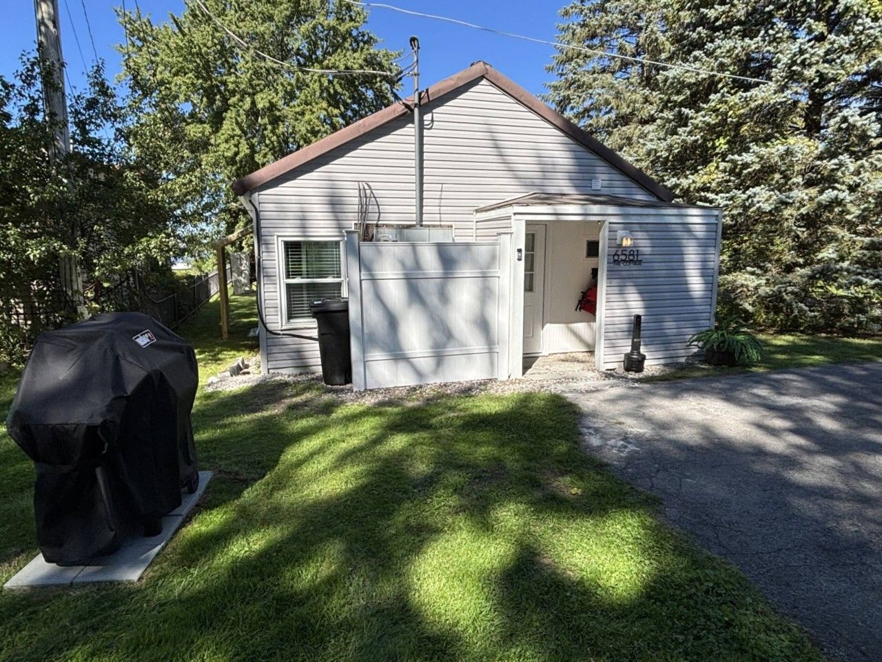 Einbungalow mit Garage, Grillüberdachung und einem gepflegten Rasen.