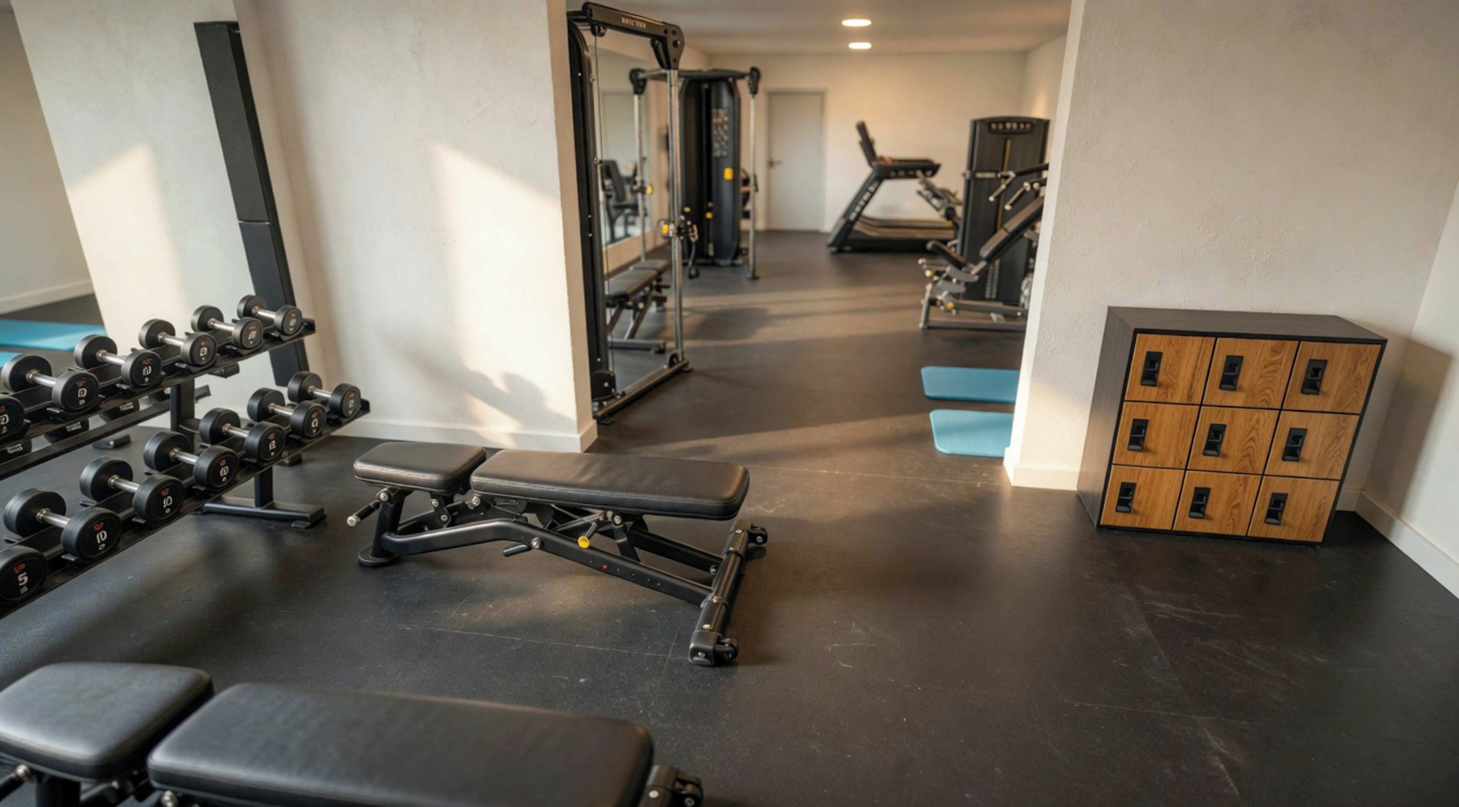 Une salle de sport équipée de matériel d’exercice, de bancs et d’un espace de rangement.