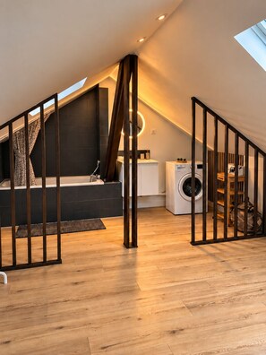 A modern loft bedroom with a sloped ceiling, a built-in bathtub, and a skylight. - The Duplex des Prébendes - Central (Tours)