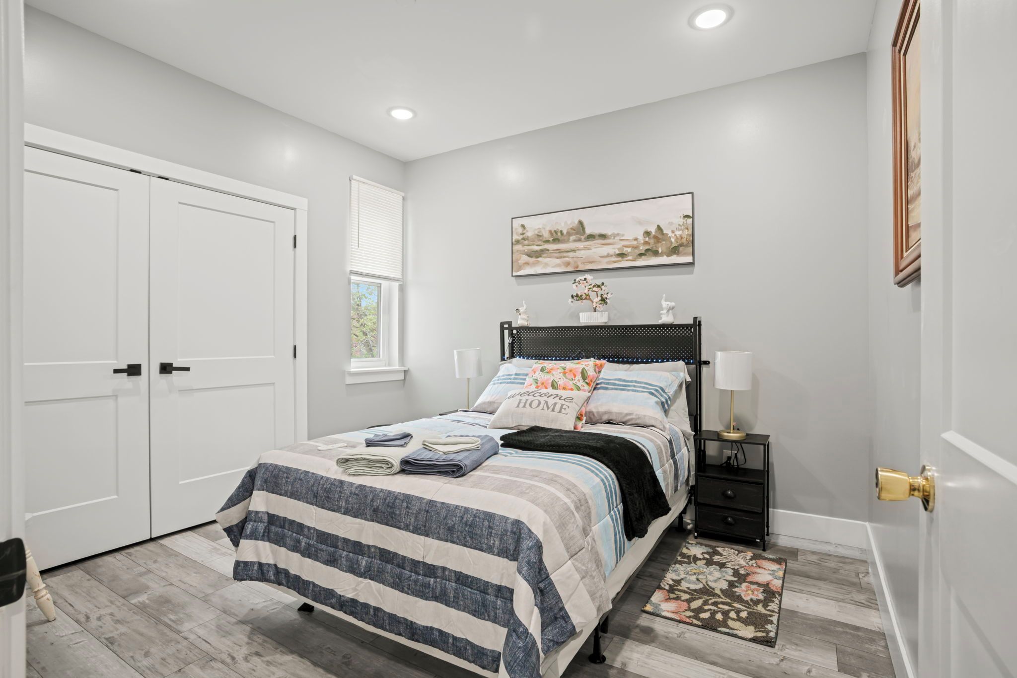 A bedroom with a bed, bedside tables, a window, and a door.