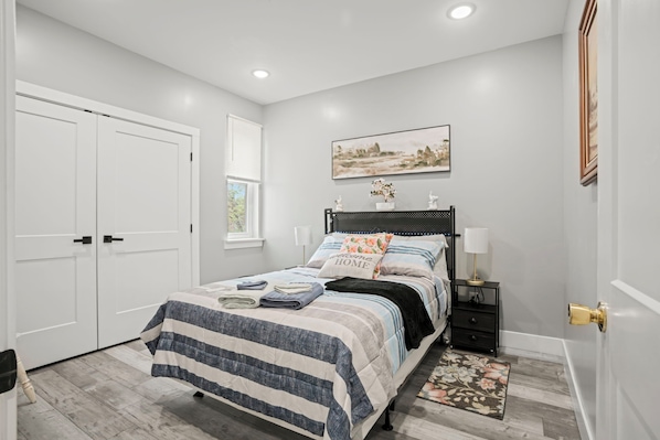 A bedroom with a bed, bedside tables, a window, and a door.