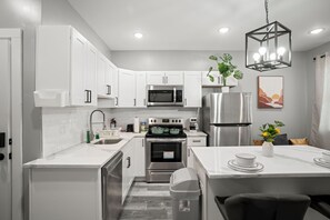 A modern kitchen with white cabinets, stainless steel appliances, and a dining area with a table and chairs.