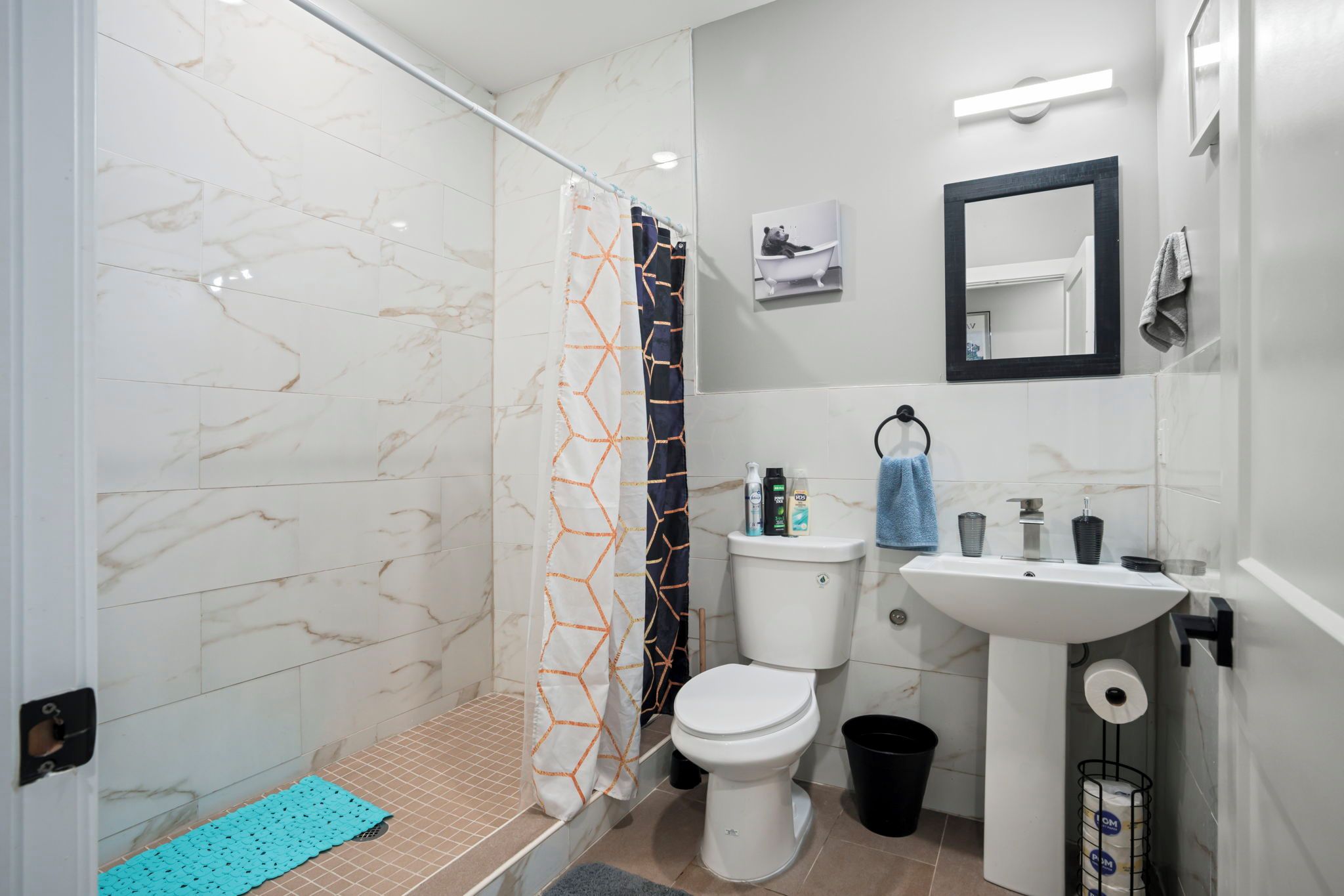A bathroom with a shower, toilet, sink, and a towel rack.