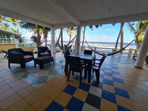 An outdoor seating area with a checkered floor, tables, chairs, and a view of the ocean.