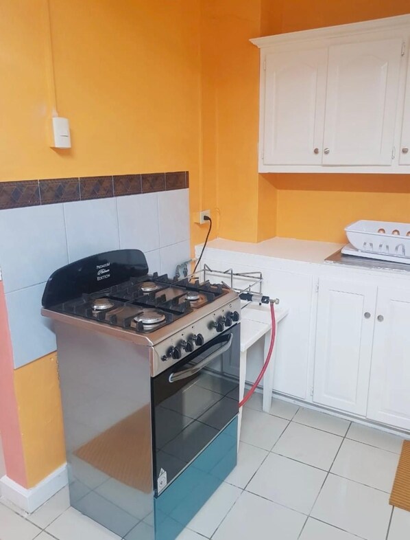 A kitchen with a gas stove, oven, white cabinets, and a tiled backsplash.