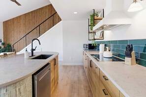 A modern kitchen with a wooden staircase, a built-in dishwasher, and a microwave.