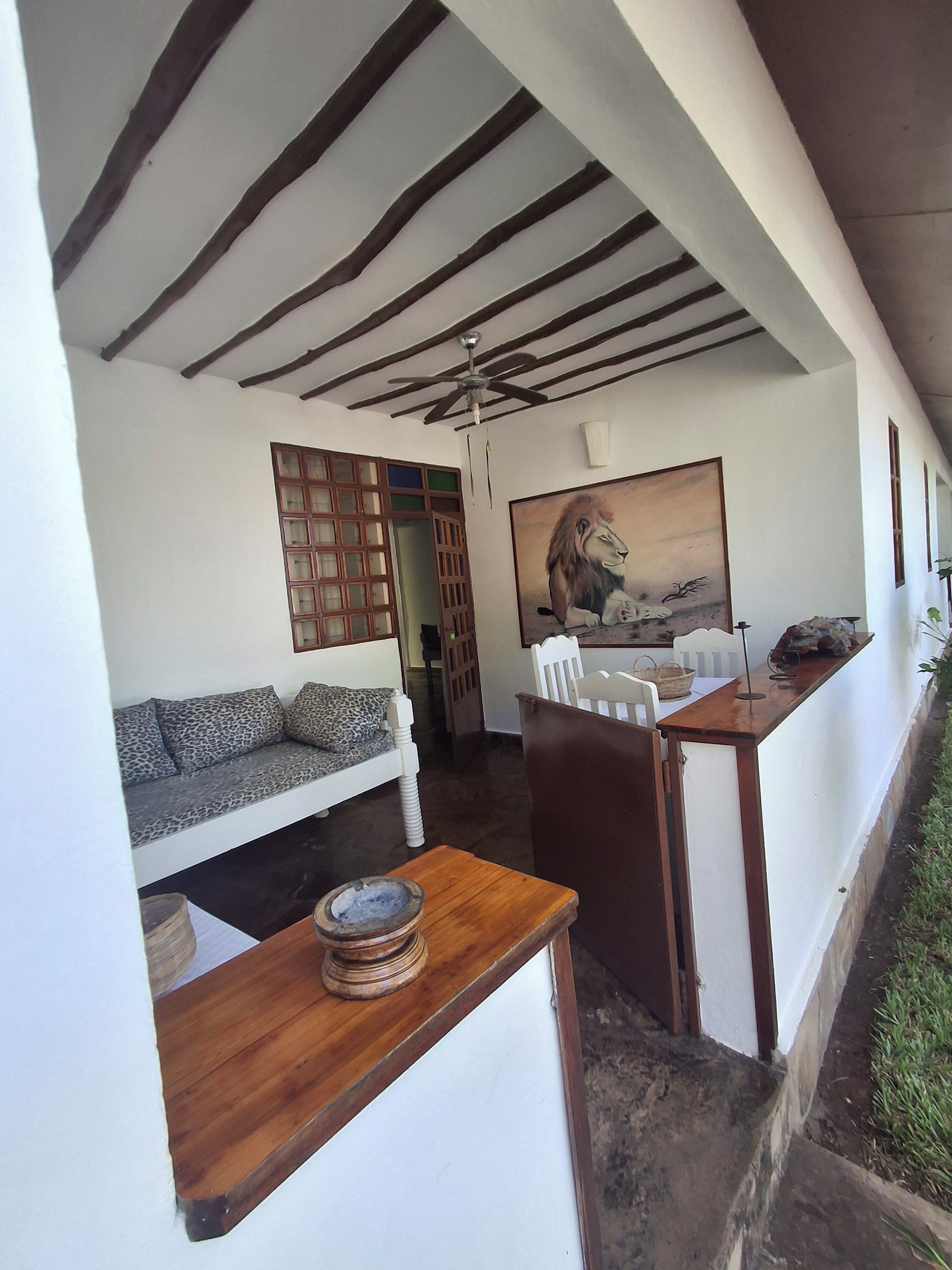A room with a sofa, a table with a bowl, a ceiling fan, and a painting on the wall.